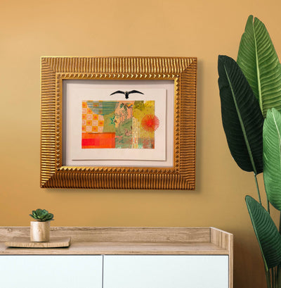 Framed artwork on a wall with a plant and console table below.
