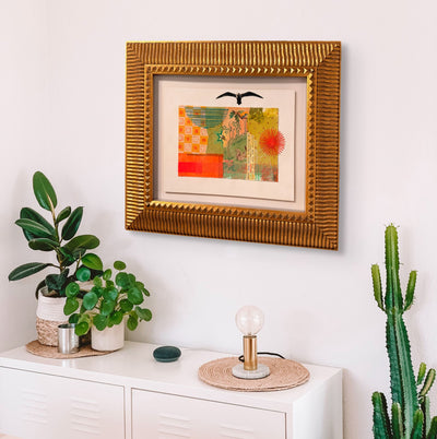 Framed artwork on a wall above a white cabinet with decorative items.