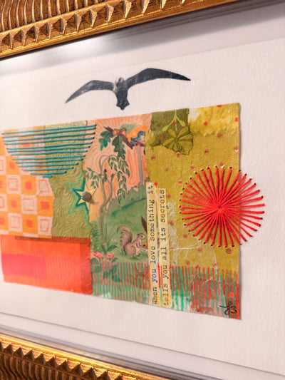 Close up shot of framed collage art with colorful patterns and a red sun-like design.